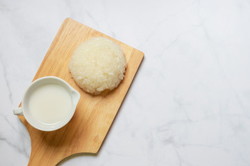 Sticky rice with coconut milk on wooden tray; usually serve with ripe mango or durian. Thai style tropical dessert, glutinous rice eat with tropical fruits.
