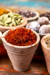 Indian spices collection, dried red saffron and another spices in clay bowls