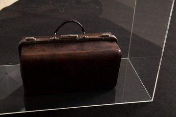 Leather carpetbag is in transparent box