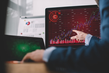 Selective focus of data analyst pointing with finger at charts on computer monitor at table