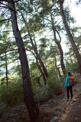 Naklejka na ściany i meble A girl with a backpack goes along a mountain trail.