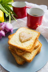 Great breakfast. Two cups of coffee, toast with peanut butter and a beautiful bright bouquet of tulips. Close-up.