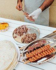 Process of making kebab. Meat on skewer. Cooker follow hygiene and use gloves. Mixed grill. Traditional arabic dish. Family dinner. Real photos of cooking