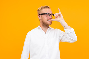 Beautiful caucasian man with glasses gesticulates isolated on yellow background