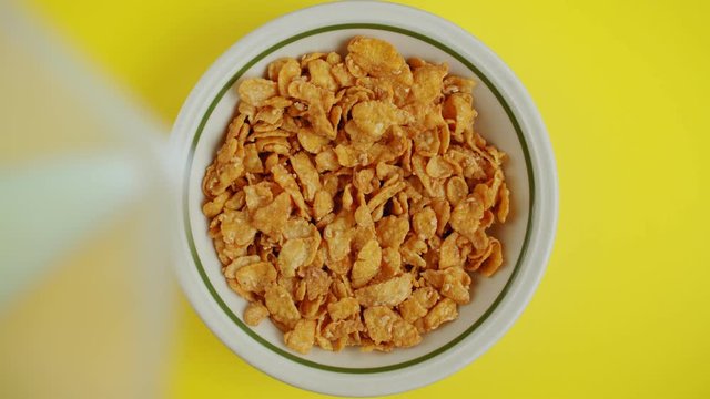 A 4K over the head shot of a bowl filled with cereal and milk being poured into the bowl. Slow motion shot. Having breakfast.