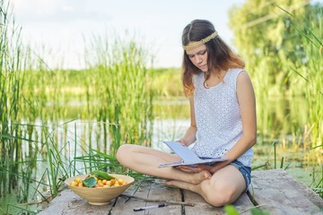 Beautiful romantic girl teenager sitting on bridge near water