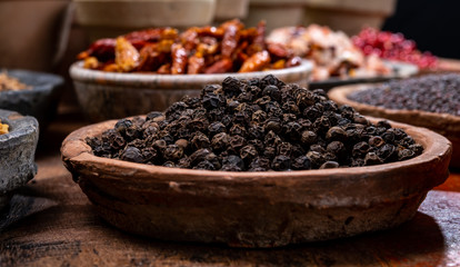 Indian spices collection, dried black peppercorns  and another spices in clay bowls