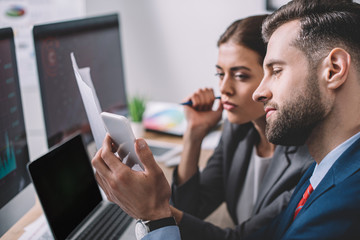 Selective focus of information security analysts using smartphone while working near computers in...