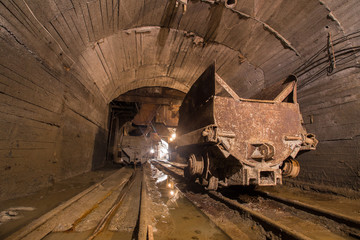 Fototapeta na wymiar Mining carts wagons with ore in gold mine underground tunnel