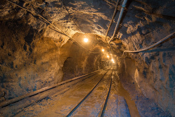 Underground gold mine shaft tunnel drift with rails and light