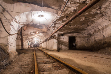 Fototapeta na wymiar Underground gold mine shaft tunnel drift with rails and light