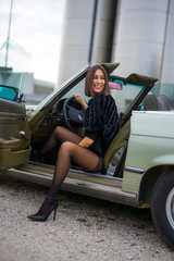 pretty girl looks and smiles as she opens a car door - obrazy, fototapety, plakaty