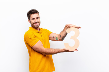young handsome man excited, happy, joyful, holding a number 3.