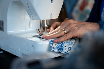 A seamstress sews material on a sewing machine.