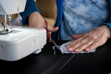 Scissors and a sewing machine are tools a seamstress uses to make homemade cover-19 corona virus protection masks.
