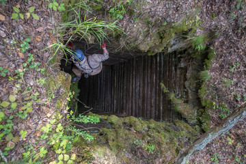 Old abandoned mine with wooden timbering and miner explorer climbing at rope