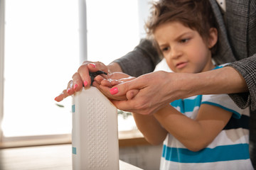 Obraz premium Mother washing hands her son carefully with soap and sanitizer, close up. Prevention of pneumonia virus spreading, protection against coronavirus pandemia. Hygiene, sanitary, cleanliness, disinfection