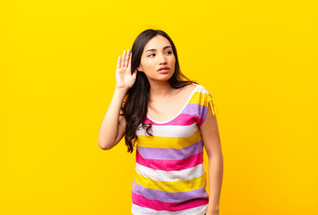young latin pretty woman looking serious and curious, listening, trying to hear a secret...