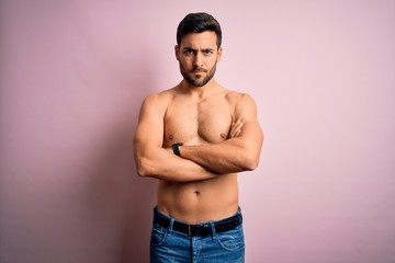 Young handsome strong man with beard shirtless standing over isolated pink background skeptic and nervous, disapproving expression on face with crossed arms. Negative person.