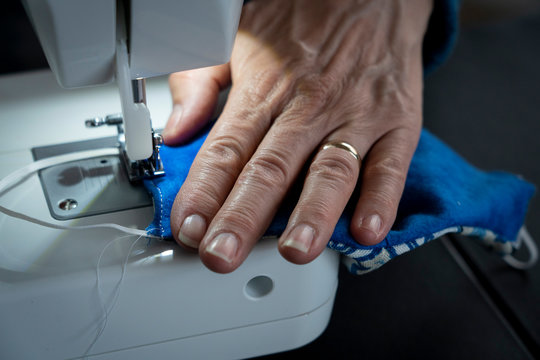A seamstress shows stitches into a homemade covid-19 coronavirus protection facemark on a sewing machine.