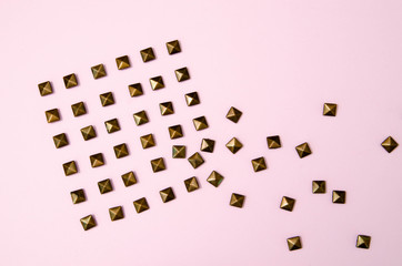 Metal rivets on pink glamourous background. Sample of stylish clothing products. Textured background. Fashionable rocker pattern.