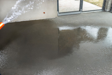 Watering a newly poured floor screed at home to prevent it from cracking.