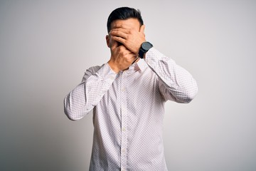 Young handsome man wearing elegant shirt standing over isolated white background Covering eyes and mouth with hands, surprised and shocked. Hiding emotion