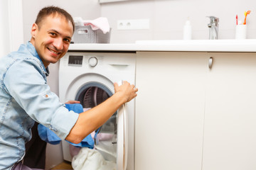 Naklejka na ściany i meble Man loading cloths to washing machine. View from inside the washing machine.