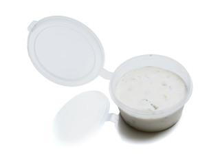 Tartar sauce in a plastic container for food delivery. Isolated on a white background with reflection