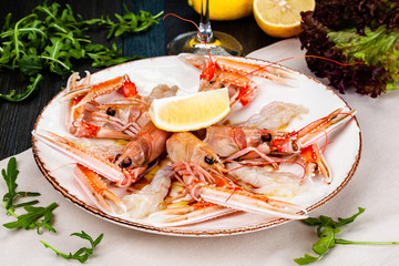 Seafood. Langoustine, scampi or Norway lobster with lemon on white plate.