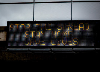 Government digital freeeway sign at overpass with message stating “Stop The Spread ,Stay Home, Save Lives” during the Coronavirus Pandemic