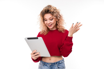 European surprised curly blonde girl with on tablet on a white background