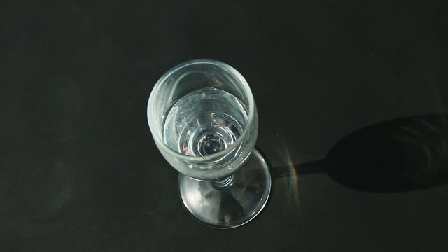 top view woman hand puts single tall crystal wine glass with water and takes it away