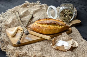 Bread with salt on a wooden board with a knife on a black background