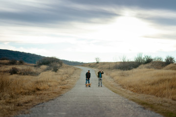 Friends with a dog hiking down the road