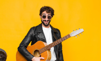 young musician man looking happy and goofy with a broad, fun, loony smile and eyes wide open with a...