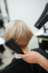 Naklejka premium Hairdresser makes hair styling with a hairdryer. Close-up on tools