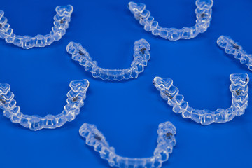 Invisible orthodontics cosmetic brackets on blue background, tooth aligners, plastic braces. A way...