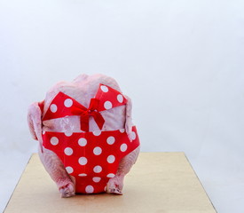 A fresh raw chicken dressed in a red polka dot bikini isolated on a clear background with copy space
