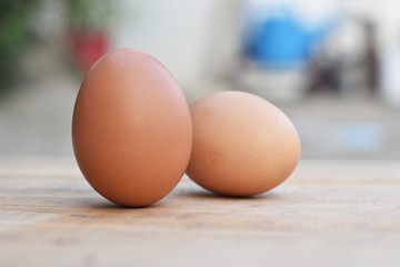 Two brown chicken eggs on a wooden table soft focus.