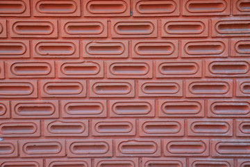 The red brick wall is orange, as background, which is made from the bricks that are ellipsoid inside, arranged horizontally and separated by layers. The wall was built for a long time.