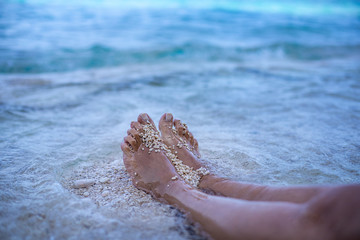 Fototapeta na wymiar Barefoot at the beach with bubbles of the wave