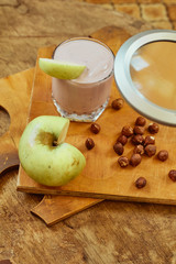 Yogurt with apple and nuts on a wooden background. Daylight.