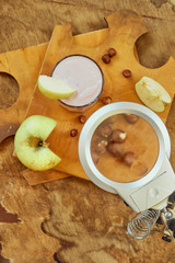 Yogurt with apple and nuts on a wooden background. Daylight.
