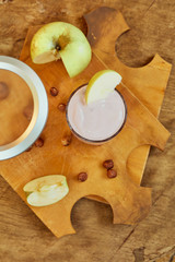 Yogurt with apple and nuts on a wooden background. Daylight.