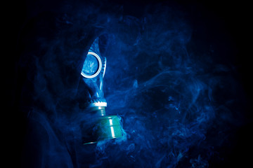 Dramatic portrait of man in gas mask and smoke on black background