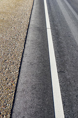 asphalt road with a gravel strip and a white roadside line