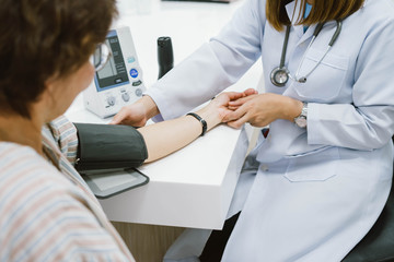 young female doctor checking senior patient  blood pressure. Health care.