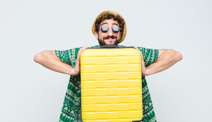 young tourist man with a suit case against white wall. travel concept