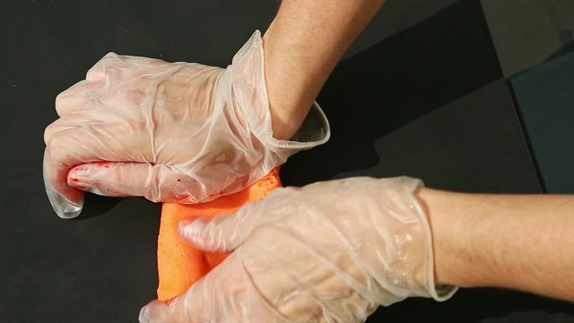 top view on woman hands in gloves knead large piece of bright orange marzipan mass